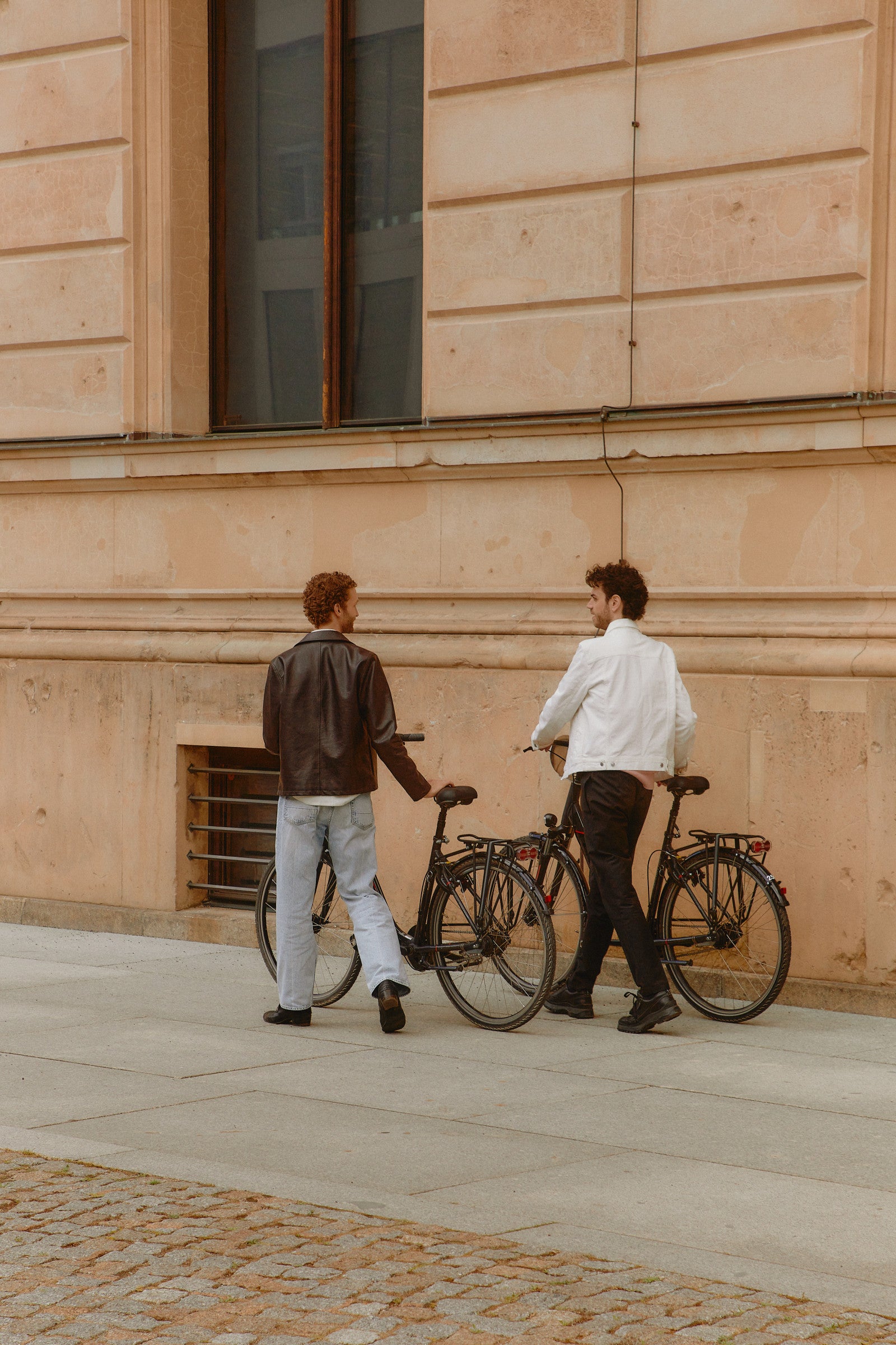 Two men on a bicycle against a wall